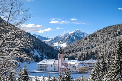 Kloster Fischingen mit Kirchturm im verschneiten Tal vor Bergkulisse