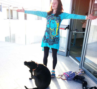 Frau in Yogaoutfit mit Hund vor dem Yogaraum im Yogaretrat in Zypern