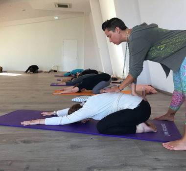 Yogalehrerin erdet den unteren Rücken einer Yogakursteilnehmerein im Retreat auf der Insel Zypern