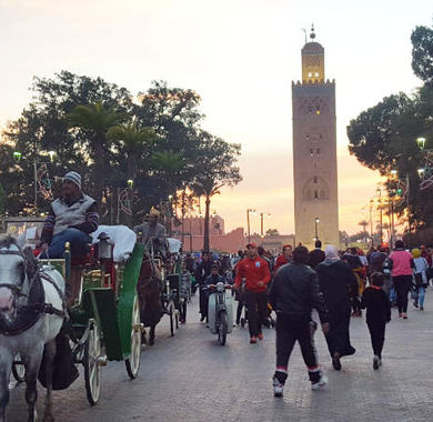 Viele Menschen bewegen sich auf den Stassen von Marrakesch mit dem Minarett. der Koutoubia-Moschee