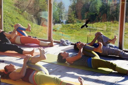 Yogagruppe in hellem Yogaraum Beindehnung im Liegen