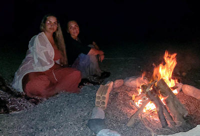 Zwei Frauen sitzen am Lagerfeuer am Strand